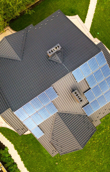 Aerial view of a private house with solar photovoltaic panels for producing clean electricity on roof. Autonomous home concept.