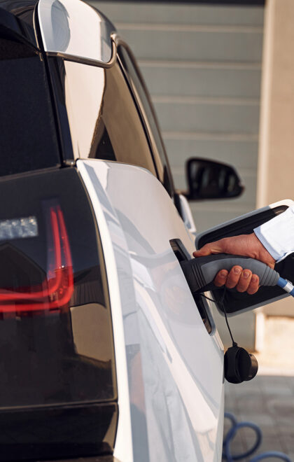 Plugged in charger. Close up view of man with his electric car.